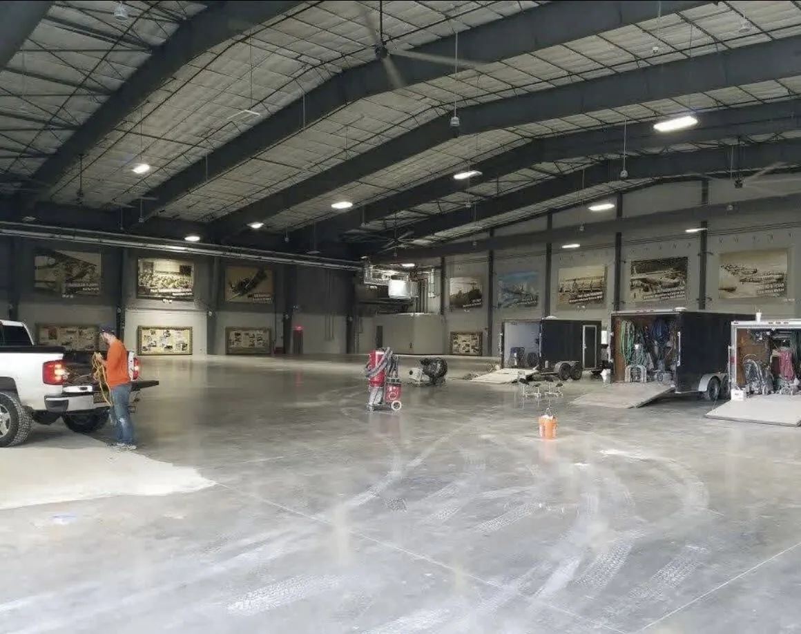 Grinders and vacuums on a bare hangar slab during prep, before the coating goes down