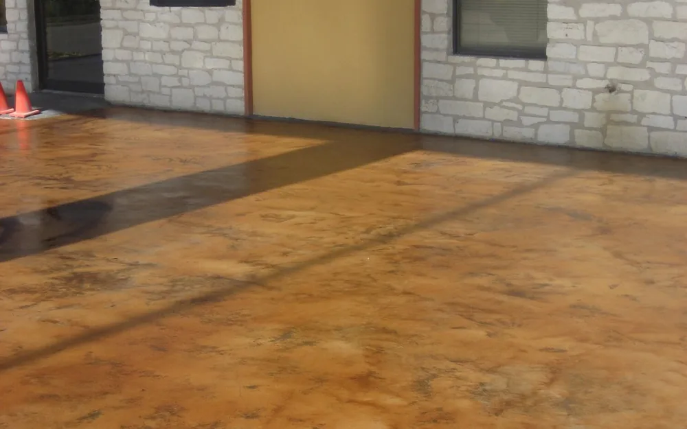 Copper acid stained concrete porch outside a stone building entrance