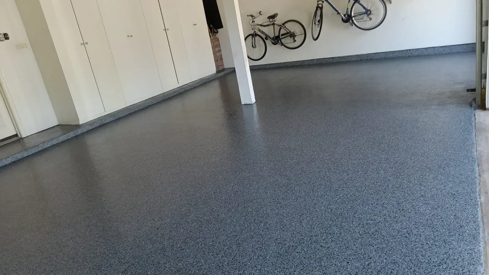 Blue gray flake epoxy floor in a home garage with bikes hung on the wall