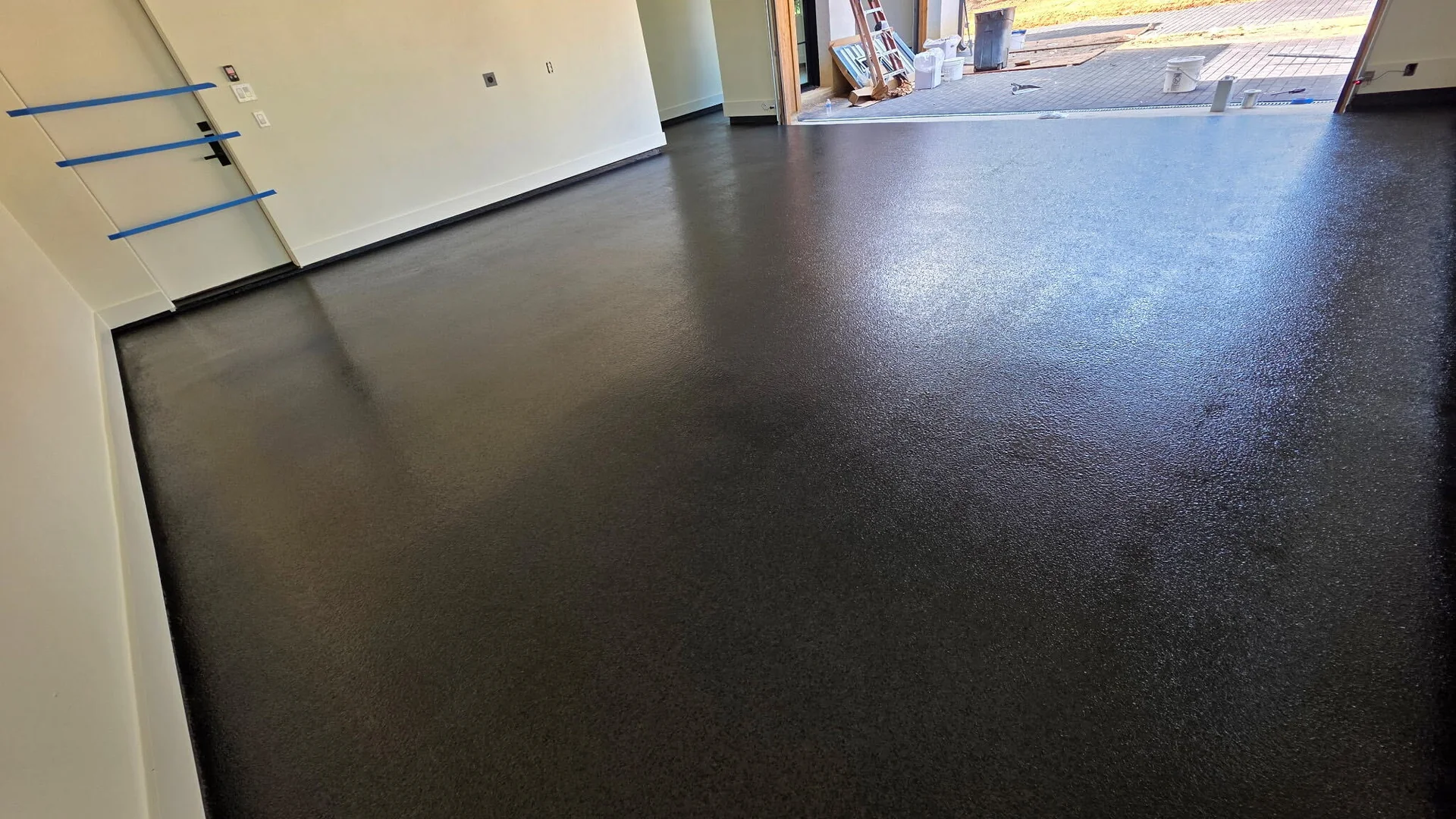 Charcoal solid-color garage floor coating with the door open to the driveway