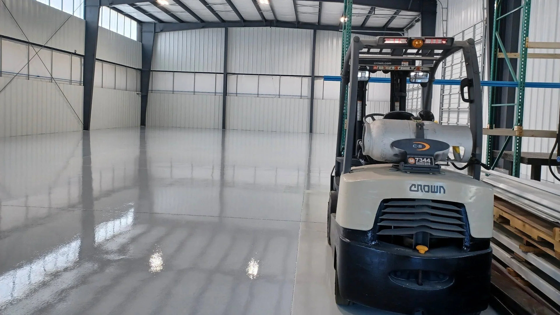 Light gray coated warehouse floor with a forklift parked by the racking