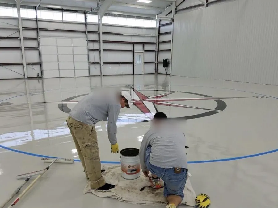 Crew taping off a compass rose on a hangar floor