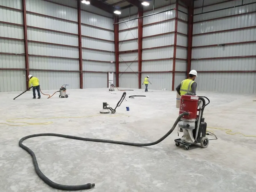 Crew grinding a warehouse slab before the coating goes down