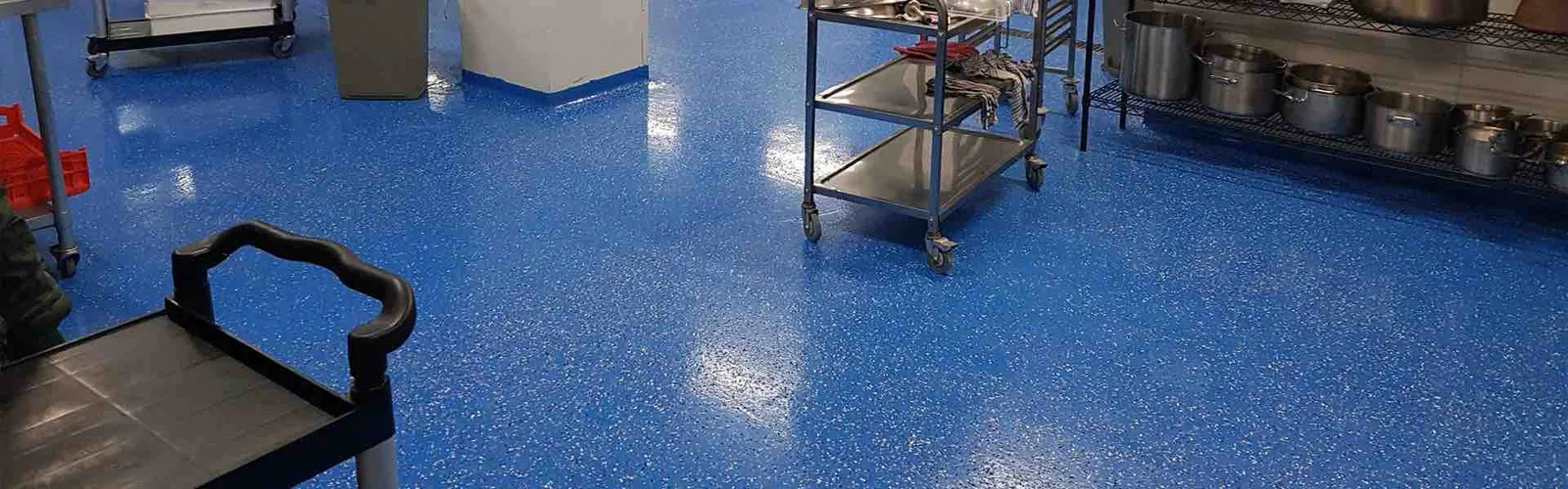 Blue quartz flake floor in a commercial kitchen with stainless carts and stock pots