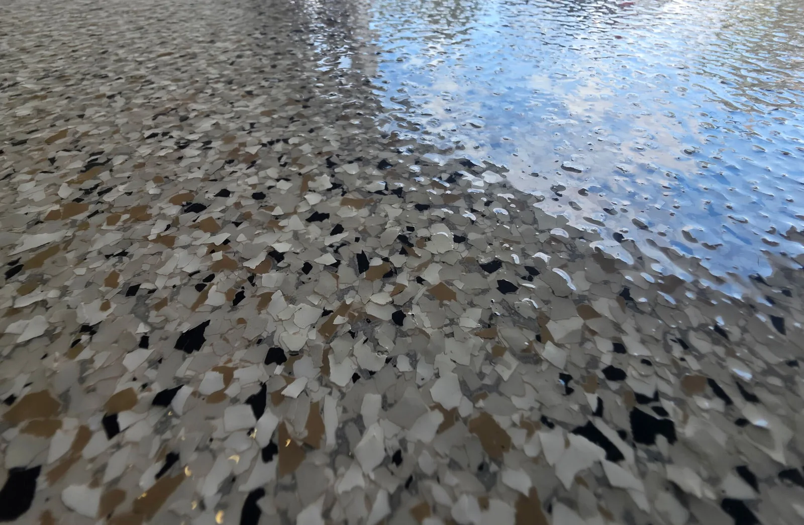 Close-up of tan, black and white epoxy flake under a glossy clear coat