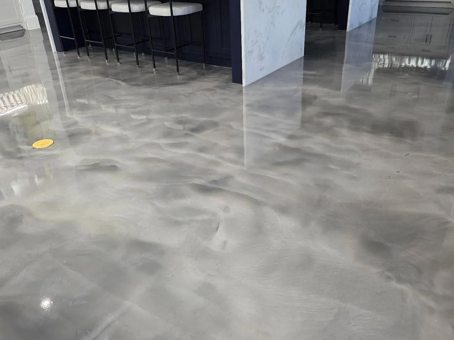 Pearl gray metallic epoxy floor in a home kitchen with a marble island