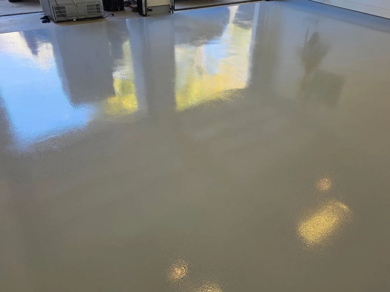Mirror-gloss gray epoxy garage floor reflecting the daylight from the open door