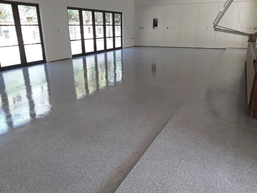 Light gray flake epoxy floor in a bright room with glass doors