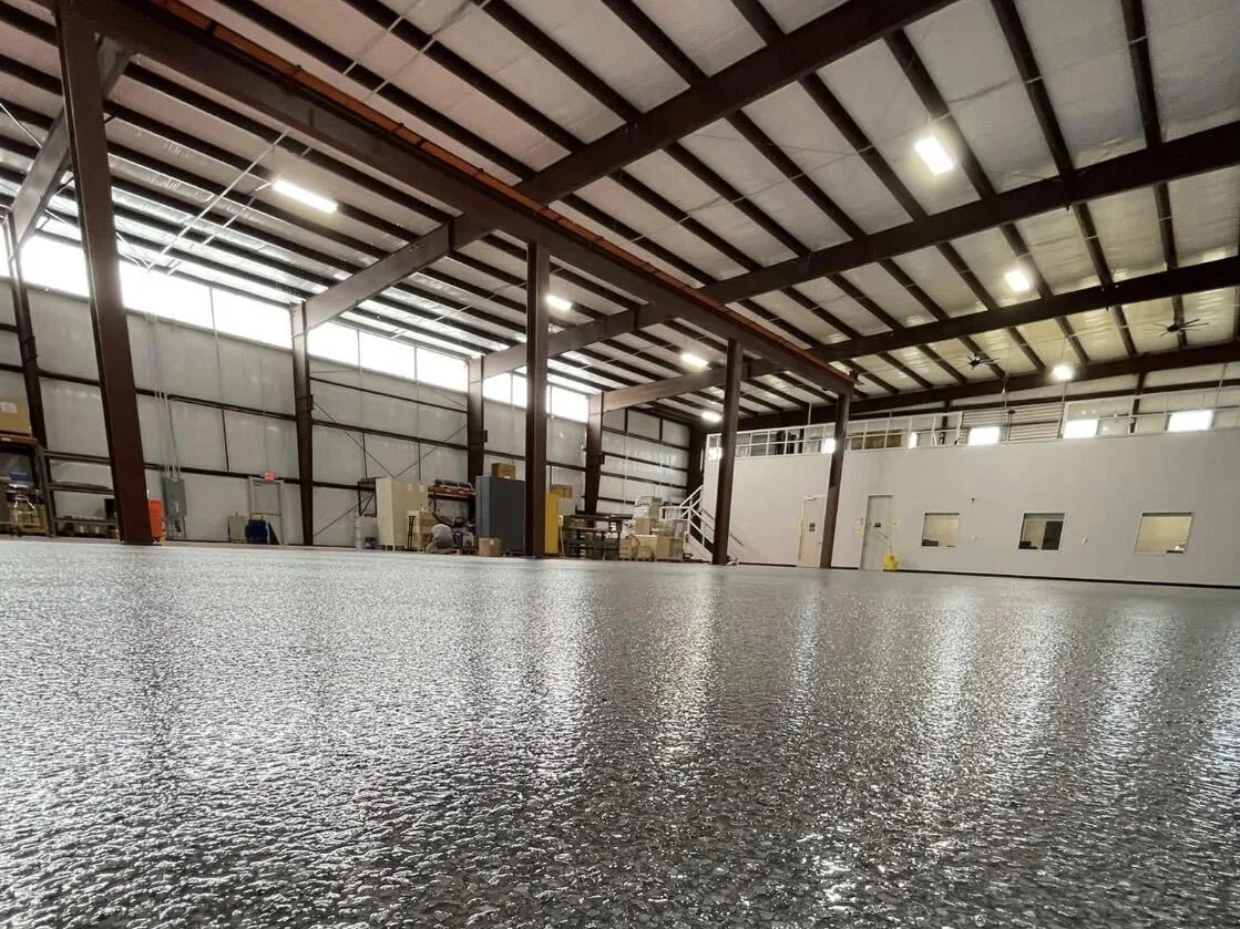 Gray flake epoxy floor across a large metal shop building