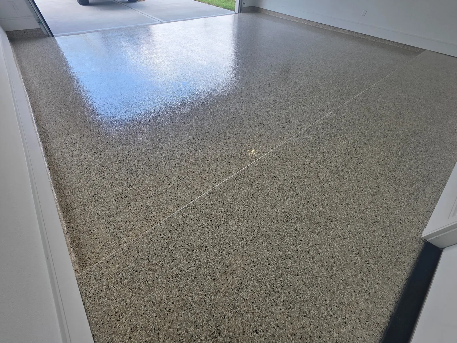Tan flake epoxy garage floor with the garage door open to the driveway