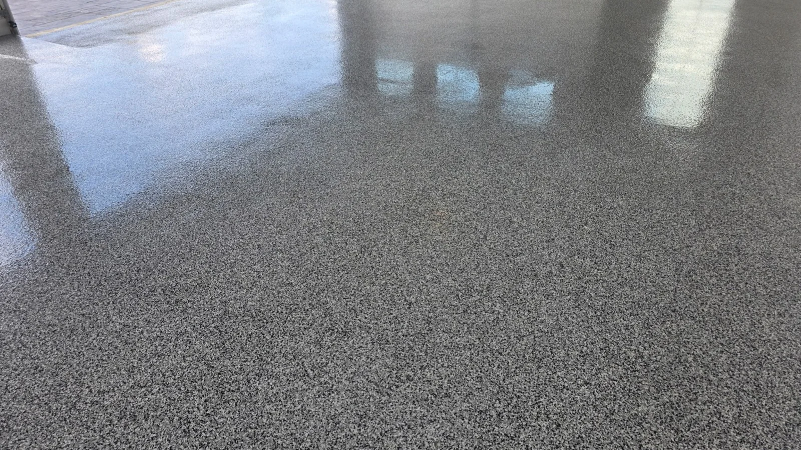 Gray and black flake epoxy garage floor with the door open to the driveway
