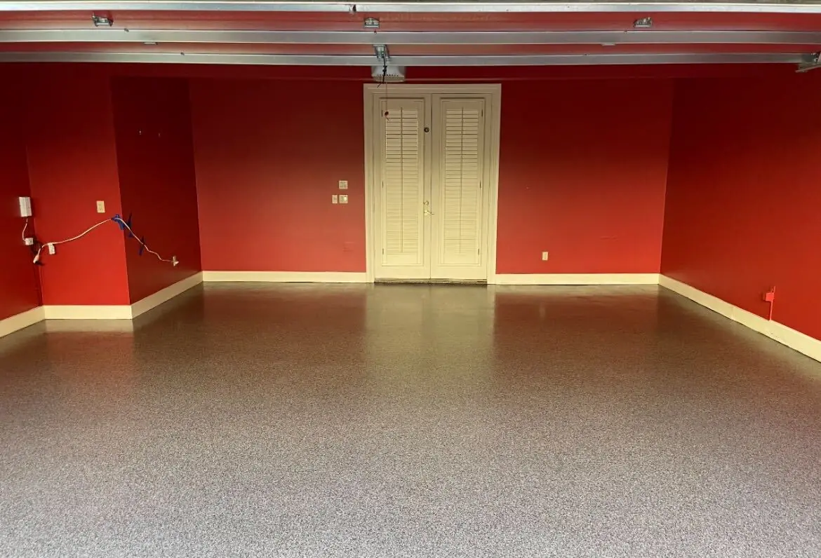 Epoxy garage floor in tan and gray flake across a red-walled two car garage in Houston, TX, shown whole