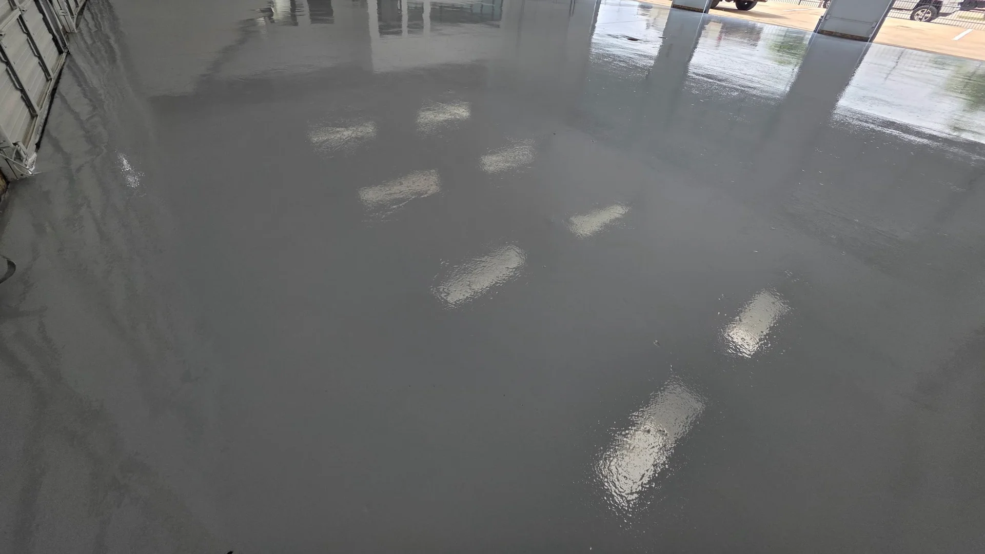 Gray solid-color epoxy floor with a high-gloss finish in a multi-bay garage