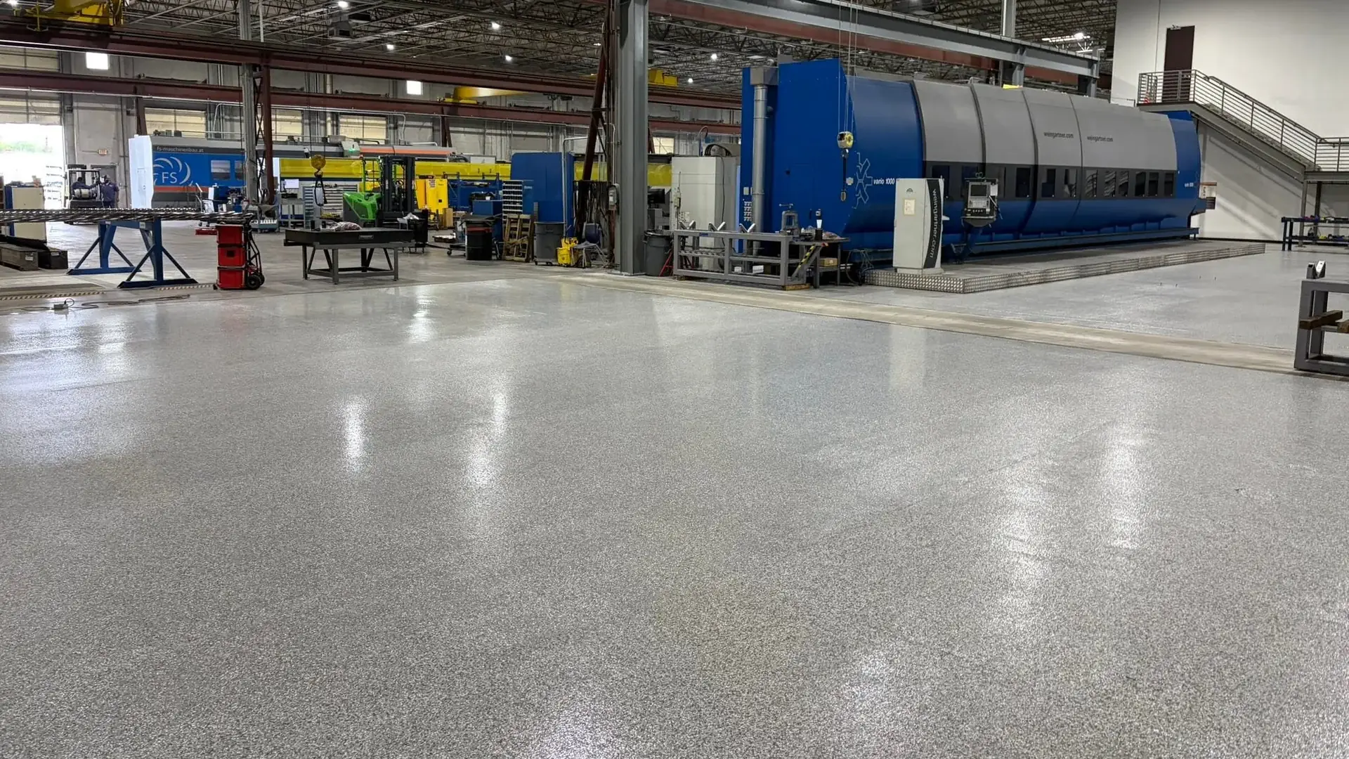 Gray flake manufacturing floor with blue and yellow walkways running between the machines