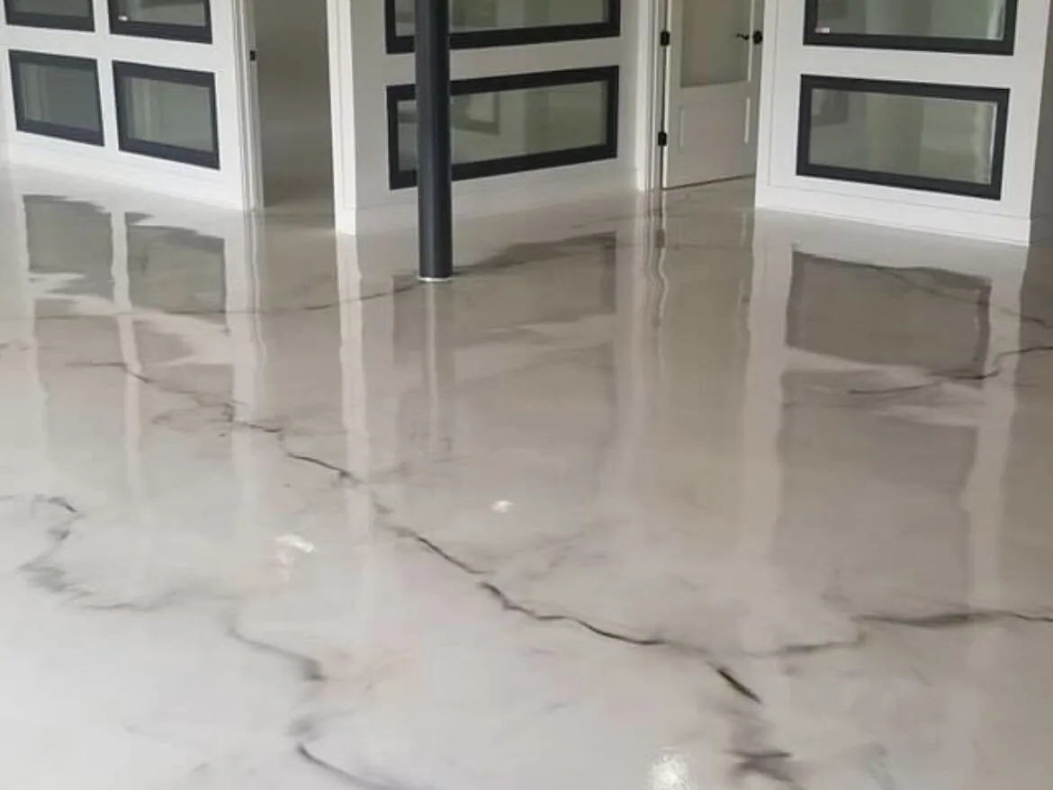 White marble-look epoxy floor with black veining in a room lined with glass doors