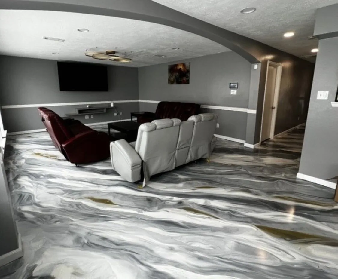 Silver and white metallic epoxy floor in a home media room with recliners