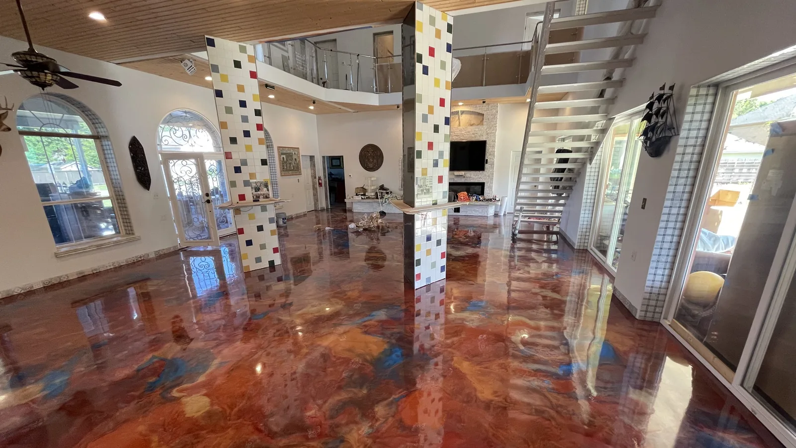 Copper and blue metallic epoxy floor across an open living area with a staircase