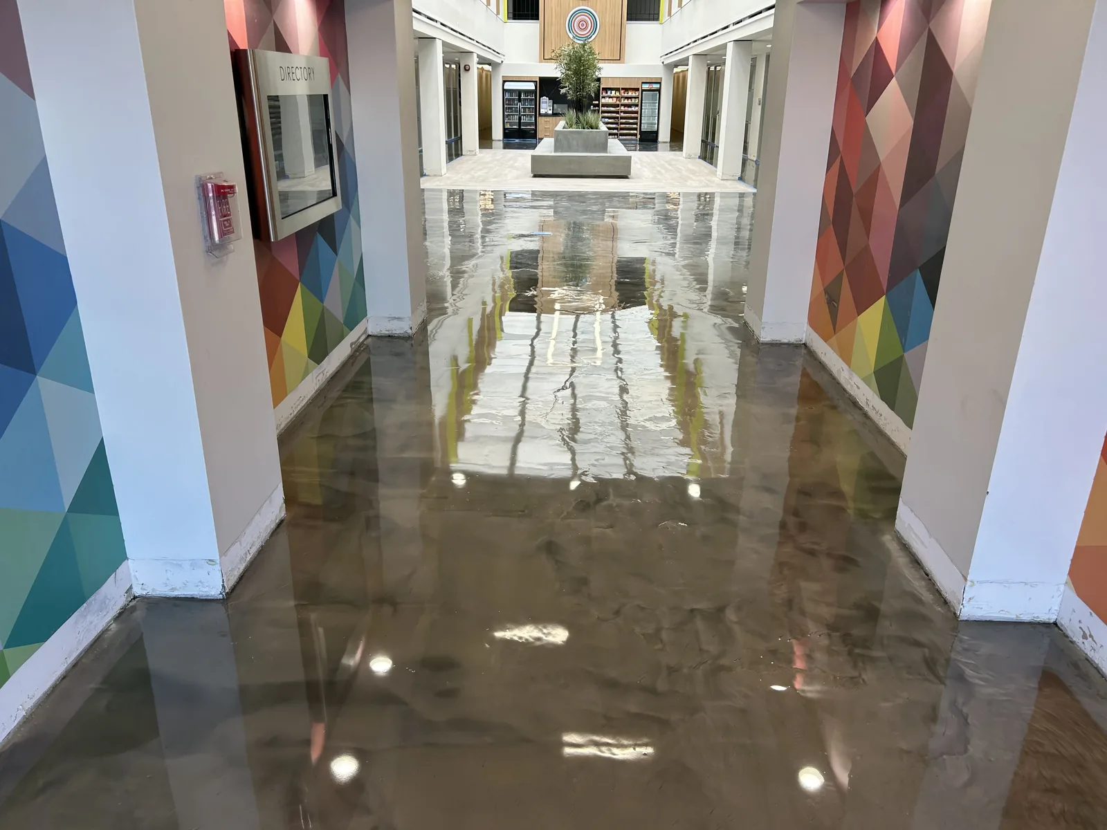 Metallic epoxy floor down an office hallway with colorful geometric wall panels