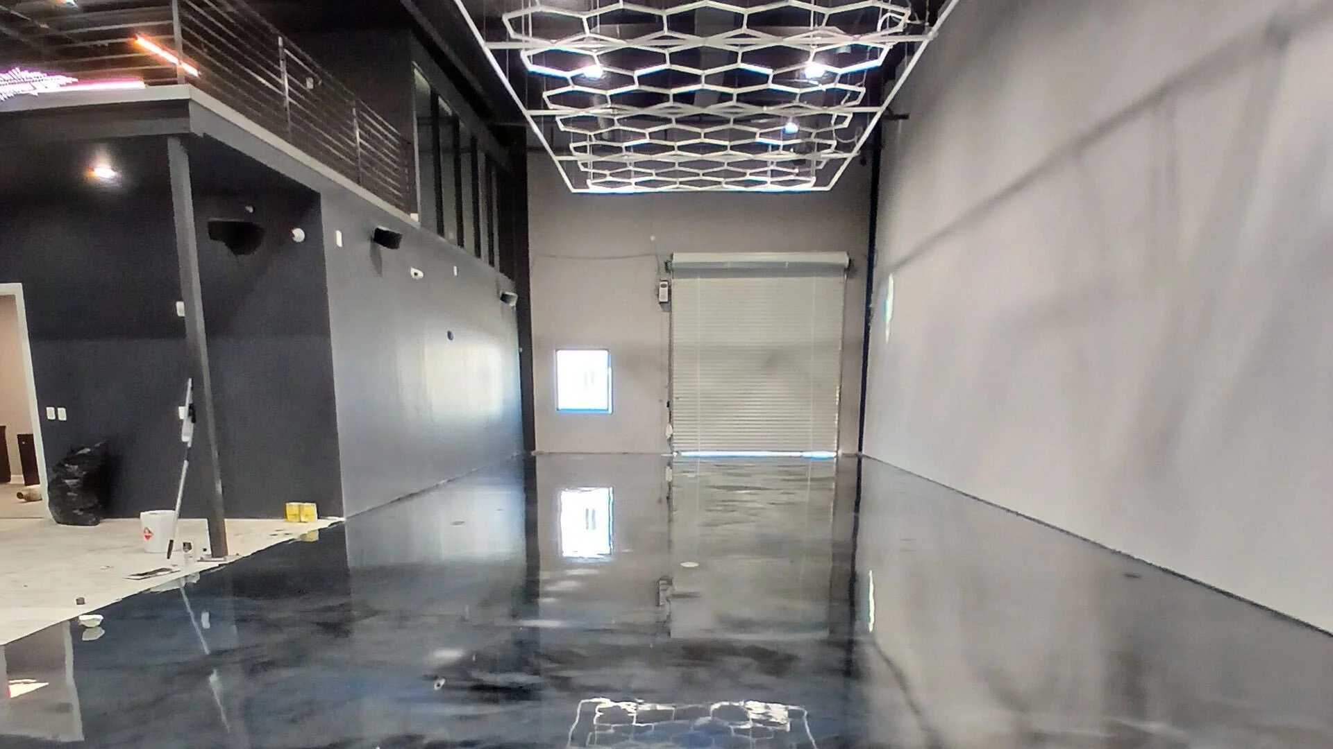 Dark metallic epoxy floor in a showroom reflecting hexagon ceiling lights