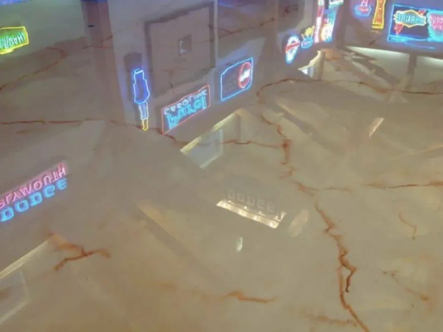 Cream and copper metallic epoxy floor reflecting neon signs