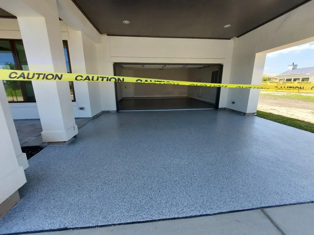 Gray flake coating on a covered outdoor slab at a Houston home, taped off while it cures