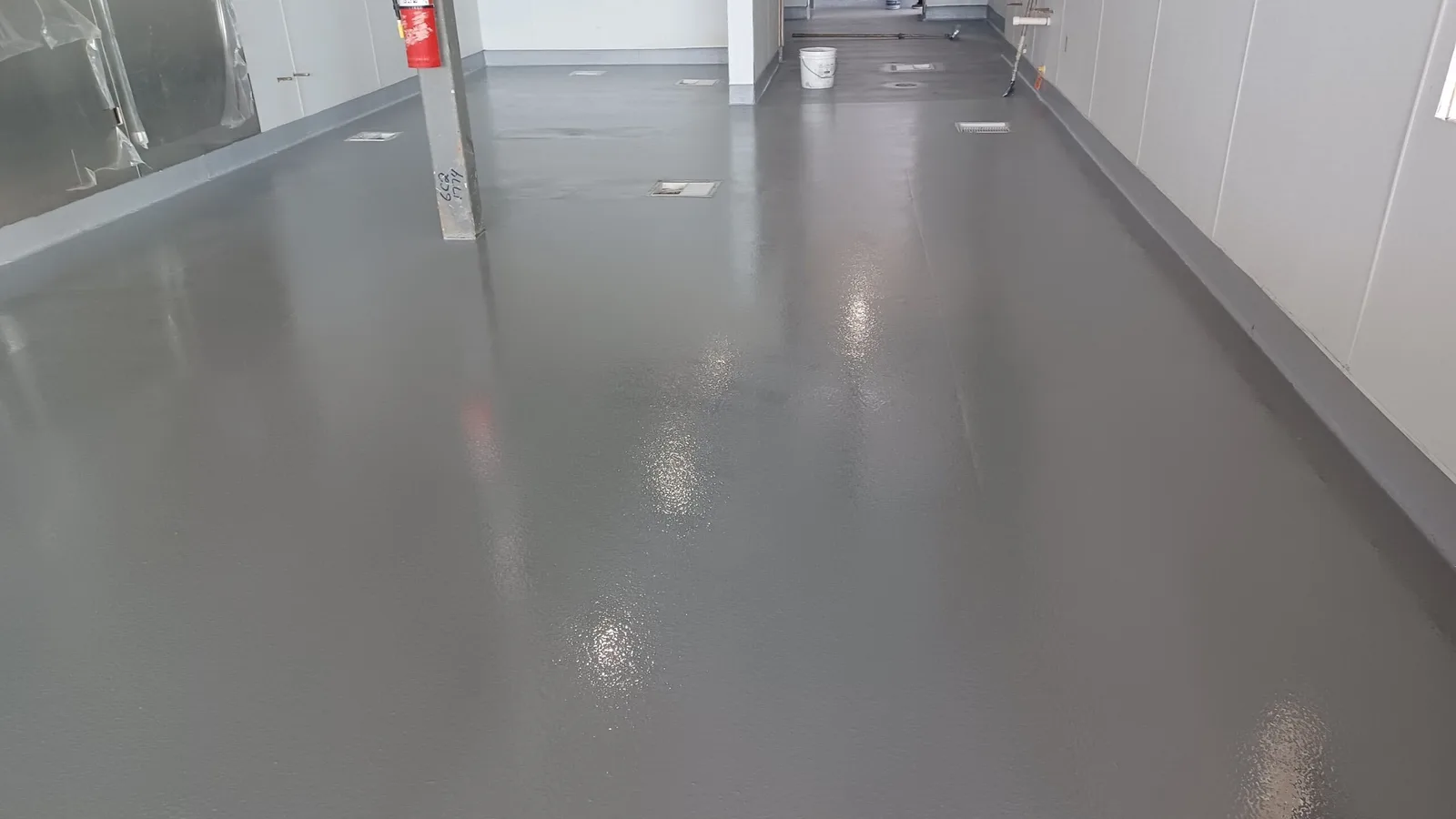 Wide gray coated floor with integral cove base and recessed floor drains