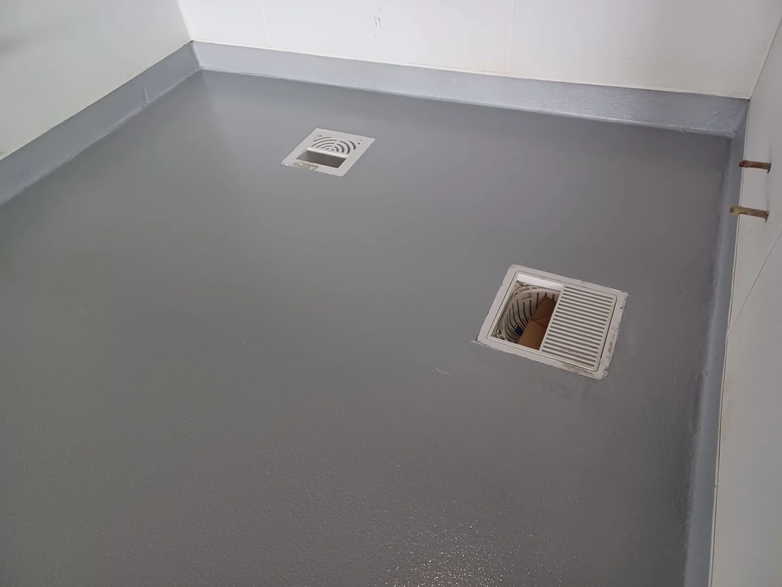 Textured gray floor coating with two floor drains and integral cove base