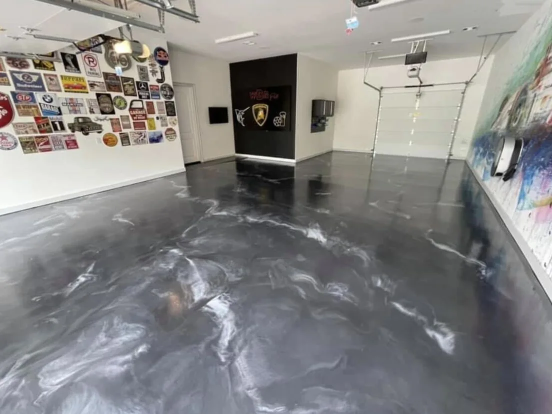 Silver gray metallic epoxy floor in a home garage with a wall of car memorabilia