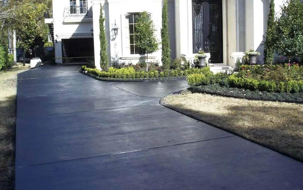 Black stained concrete driveway curving up to a two-story home