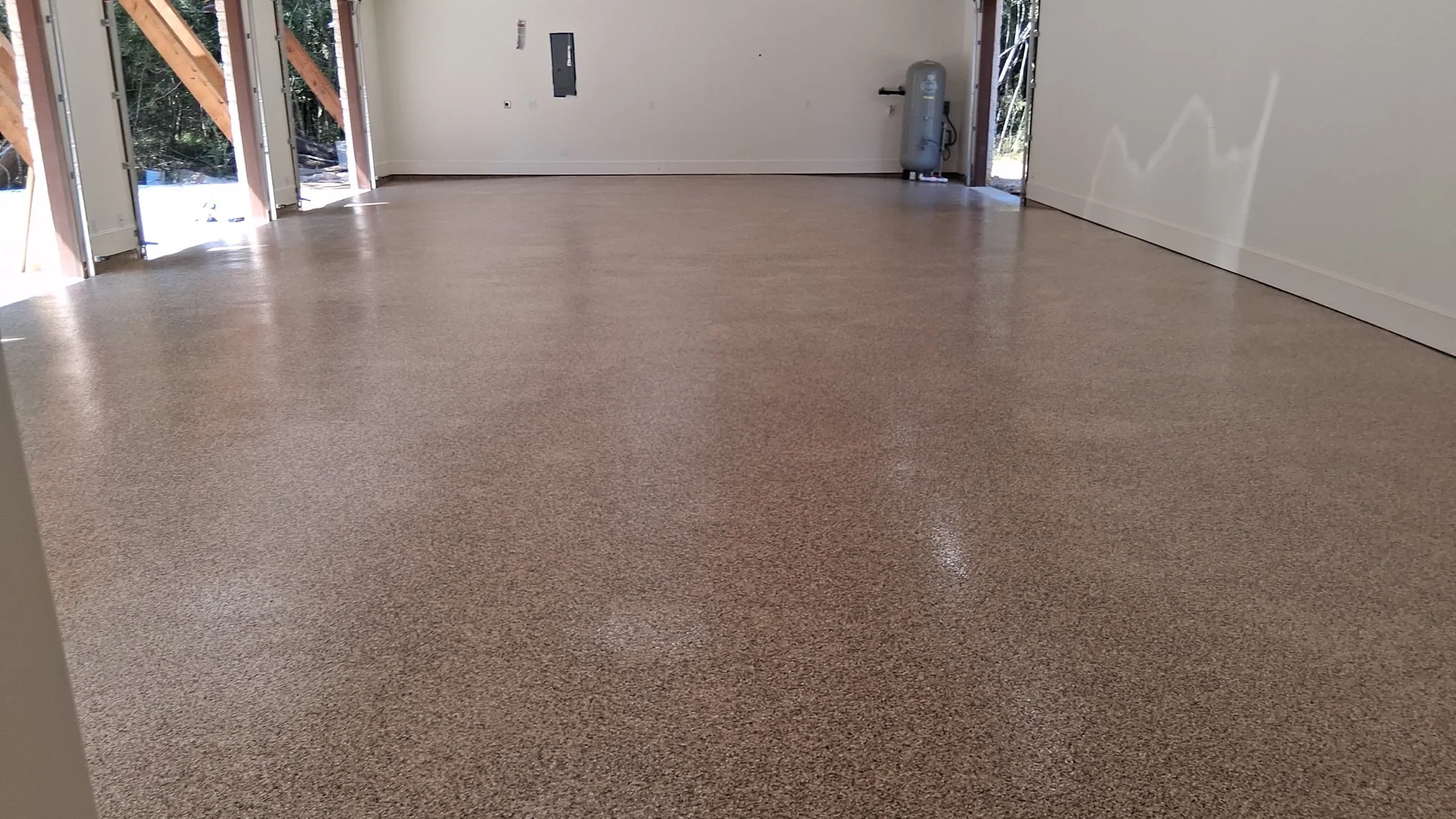 Tan flake epoxy garage floor in a large garage with the doors open