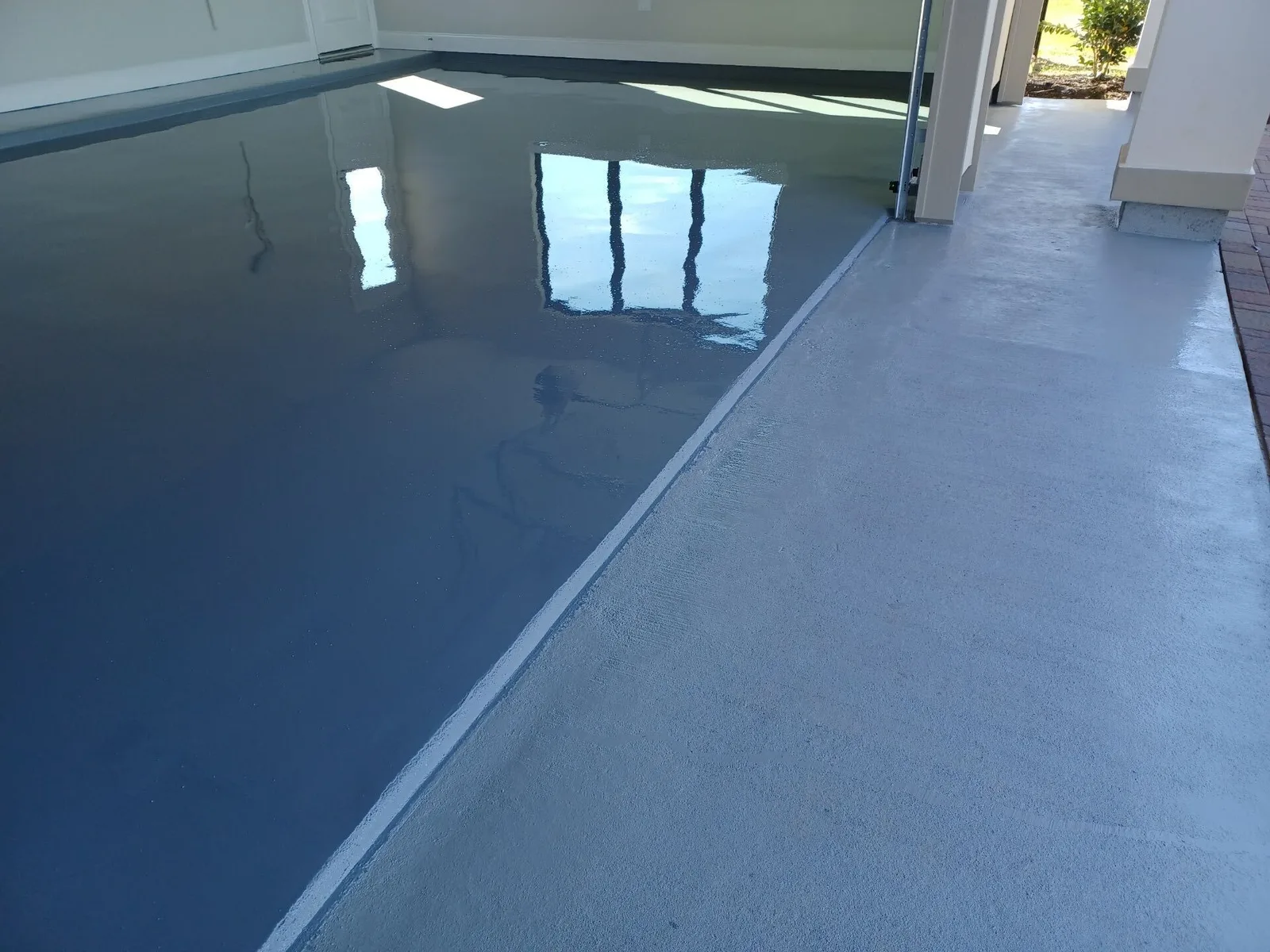 Mirror-gloss gray solid-color garage floor coating with the door open to the driveway