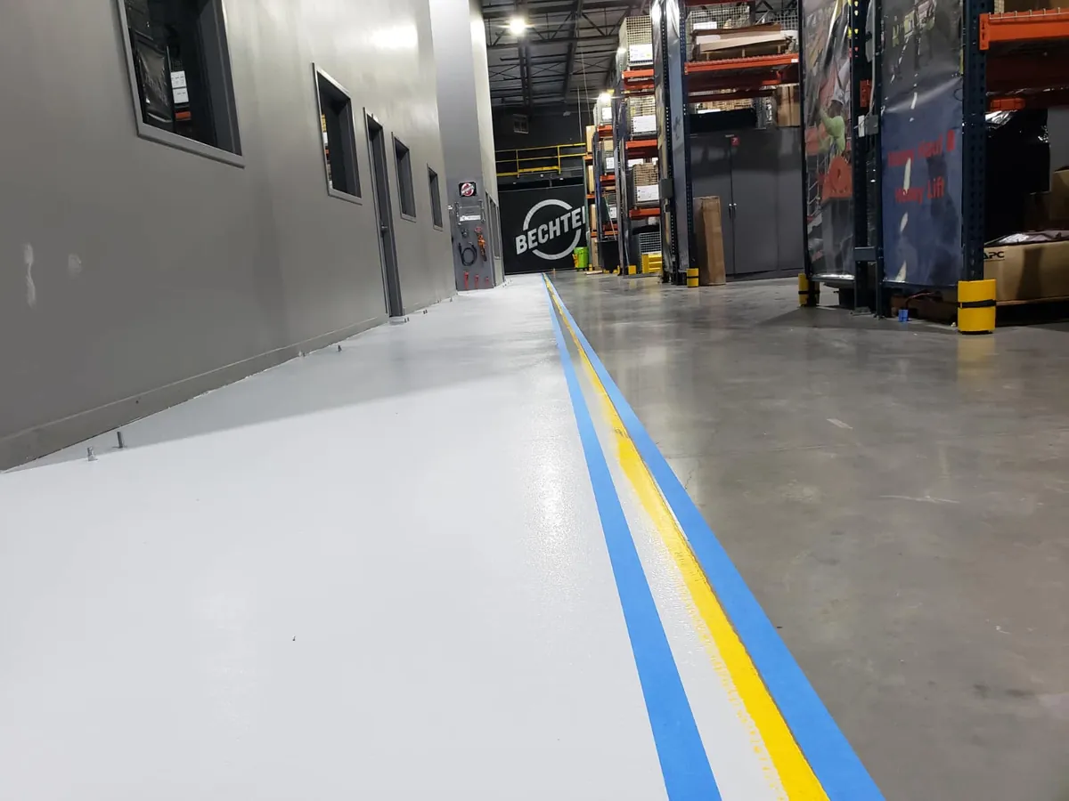 Long coated walkway with blue and yellow safety lines through the warehouse