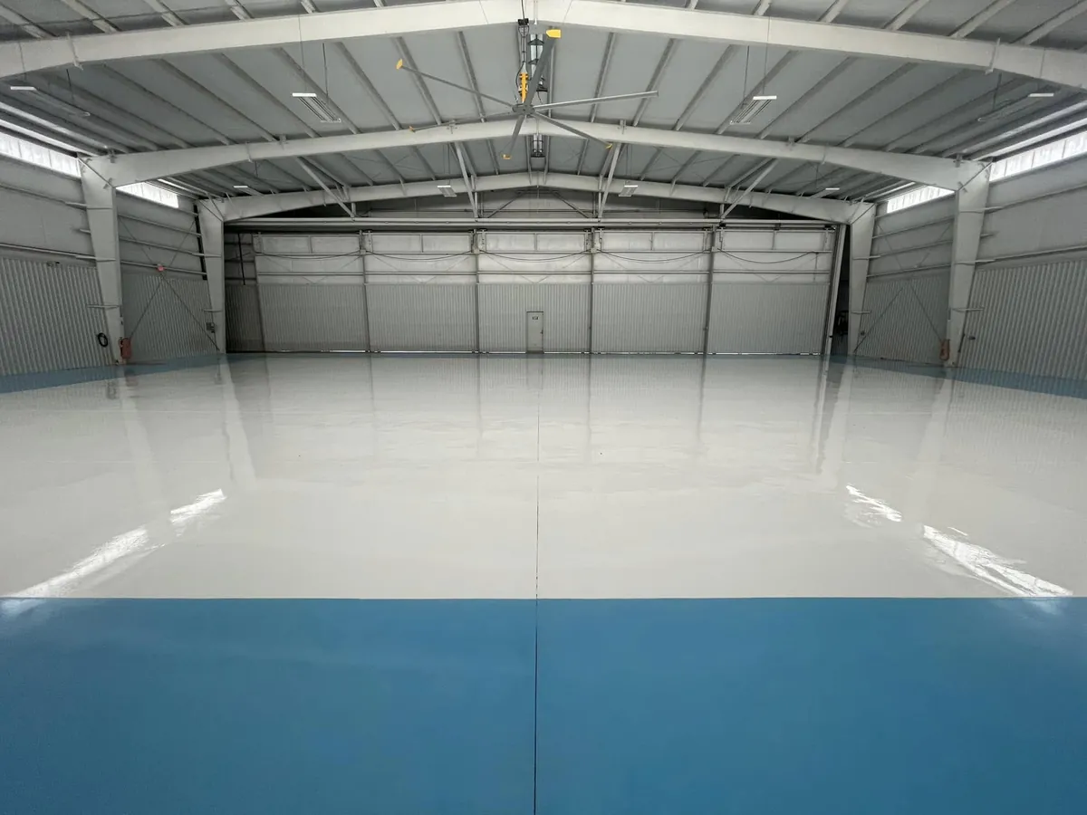 White hangar floor with a blue border and the hangar sign in the distance