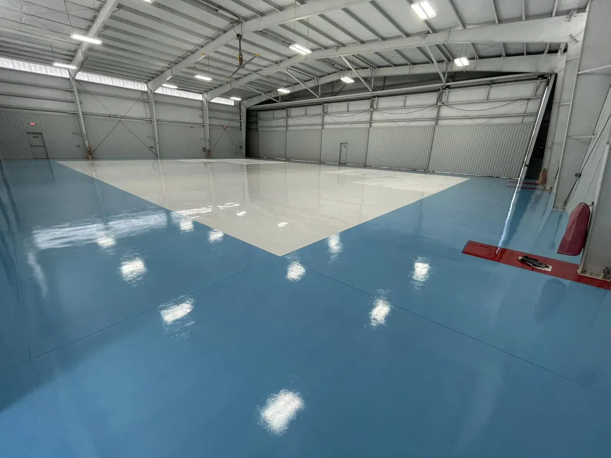 High-gloss white hangar floor with a wide blue apron