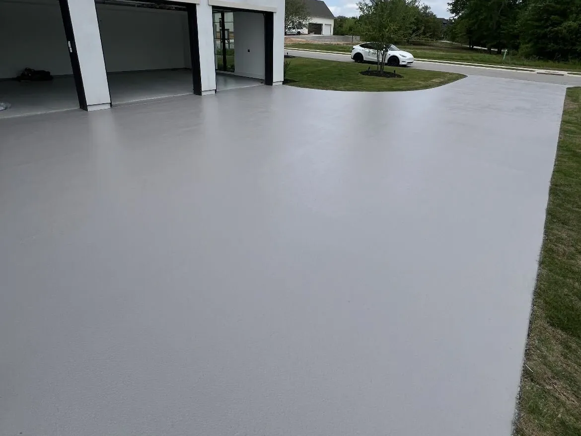 Coated gray driveway apron in front of a home with three garage doors
