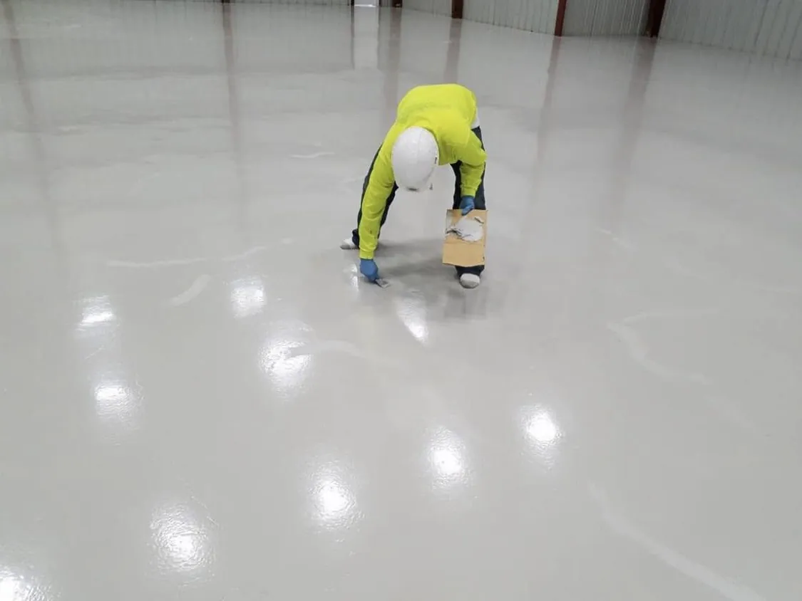 Crew member in a high-visibility jacket detailing a white coated floor