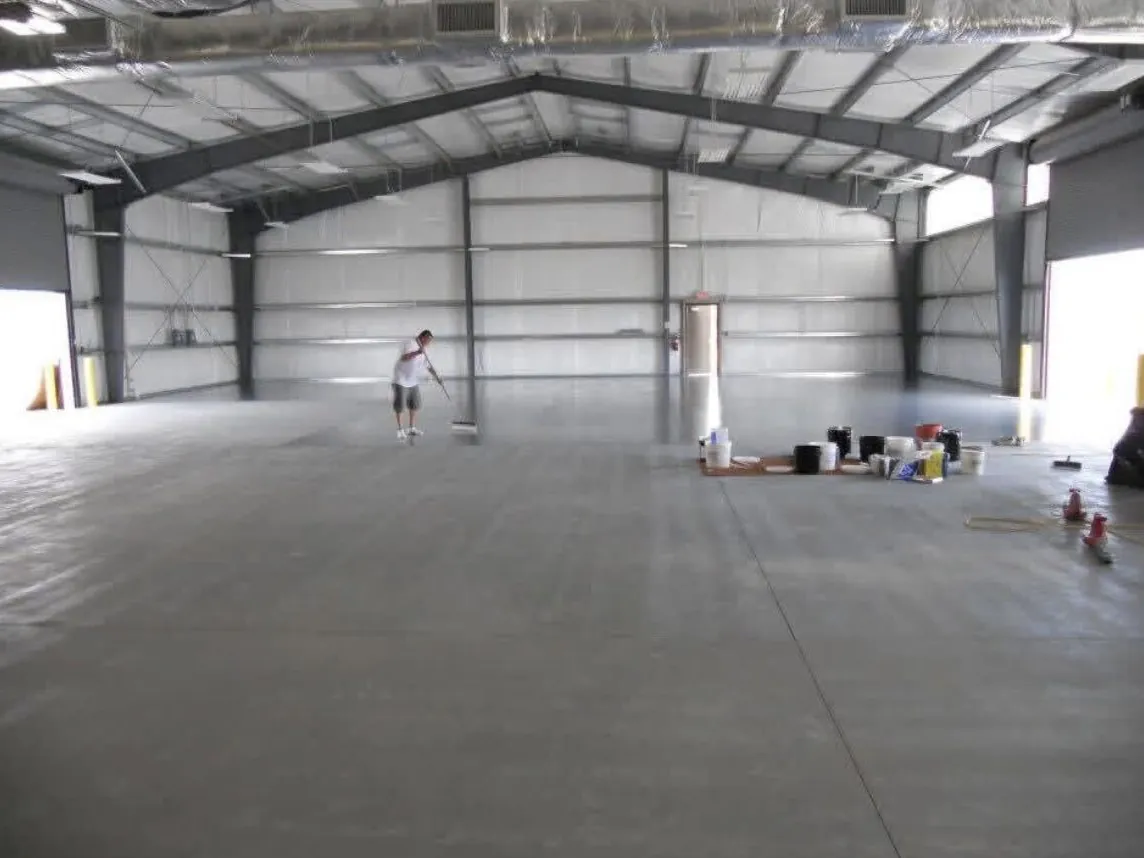 Crew rolling a floor coating across a large warehouse