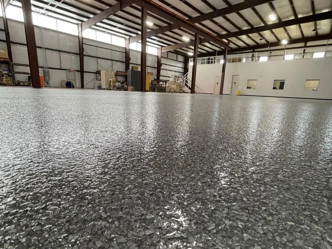 Gray flake epoxy floor across a large metal shop building