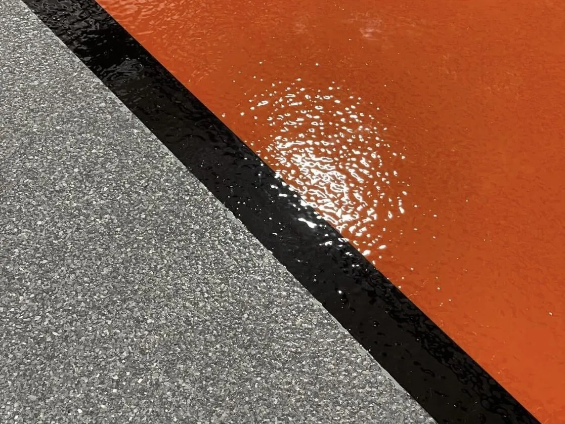 Orange safety walkway coating with a black border on a flake floor