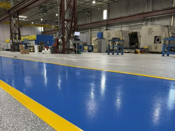 Gray flake plant floor with a blue and yellow walkway between the machines