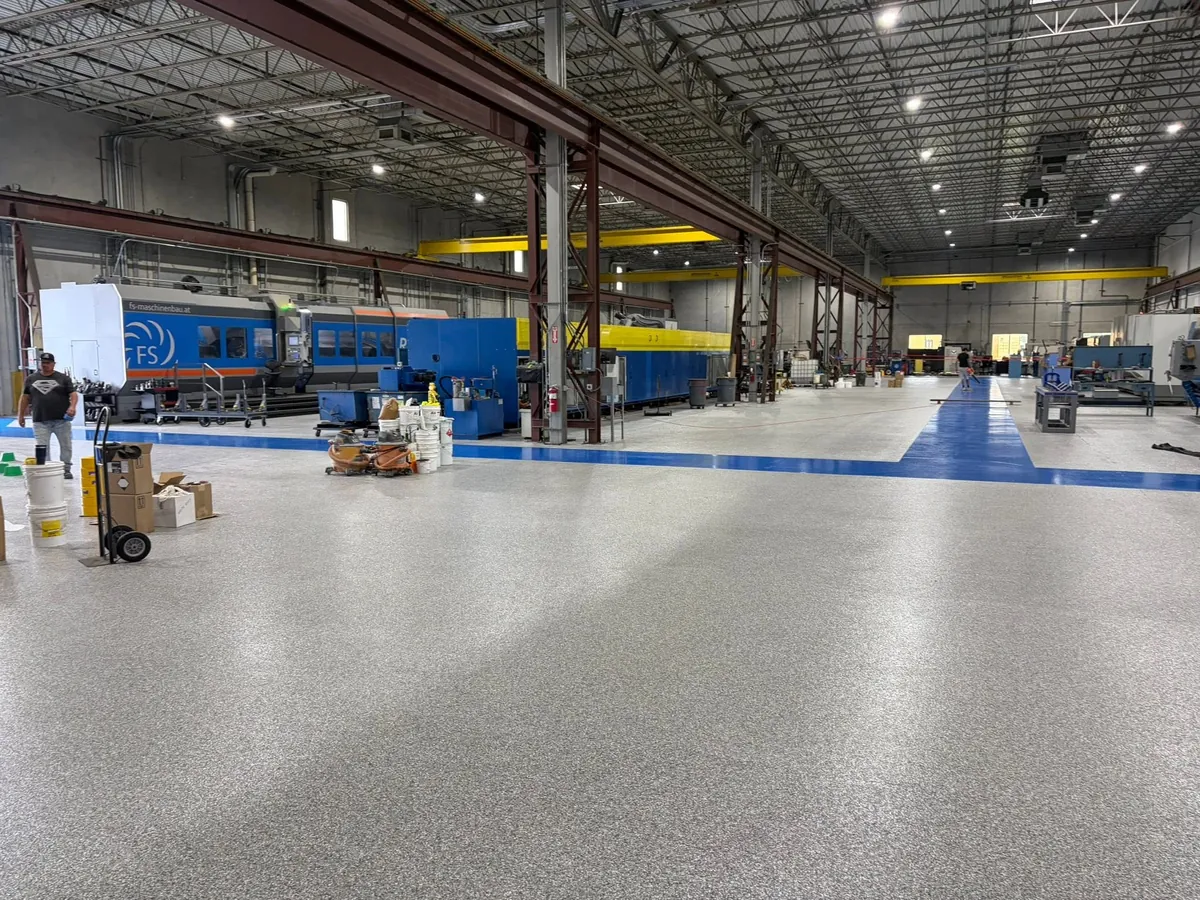 Blue walkway running between machines on a gray flake plant floor