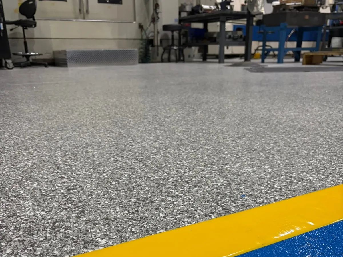 Gray flake plant floor with a blue safety stripe along the machine line