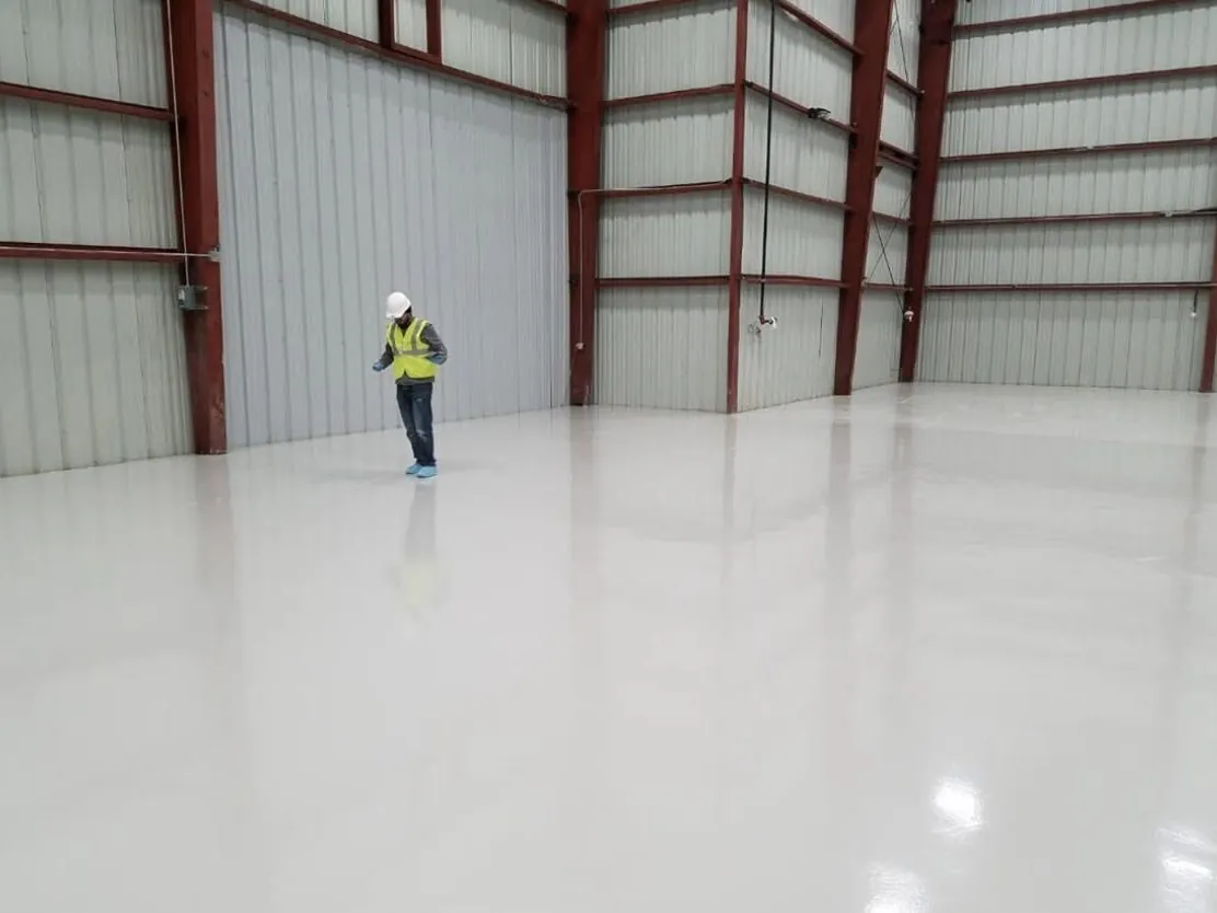 Crew member checking a freshly coated white warehouse floor