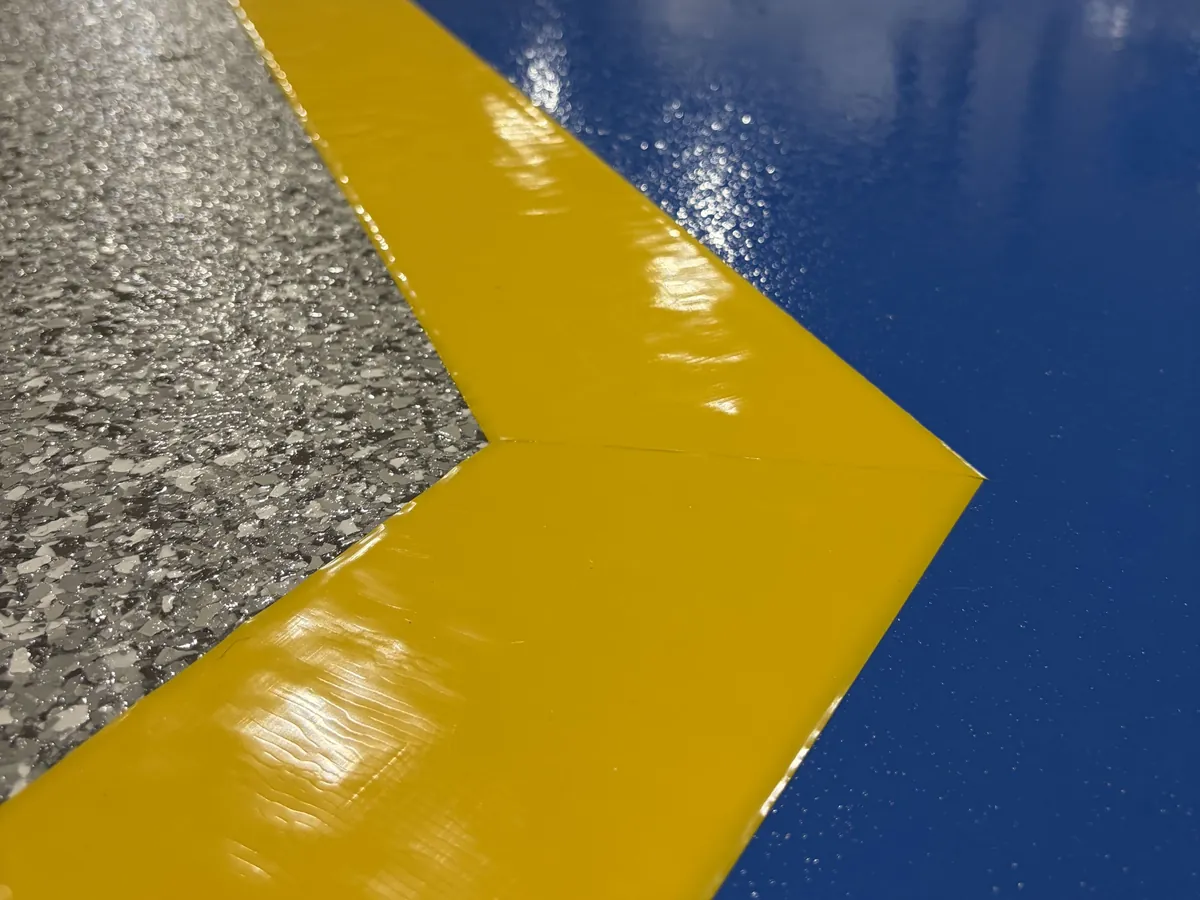 Yellow and blue safety stripe beside a gray flake floor